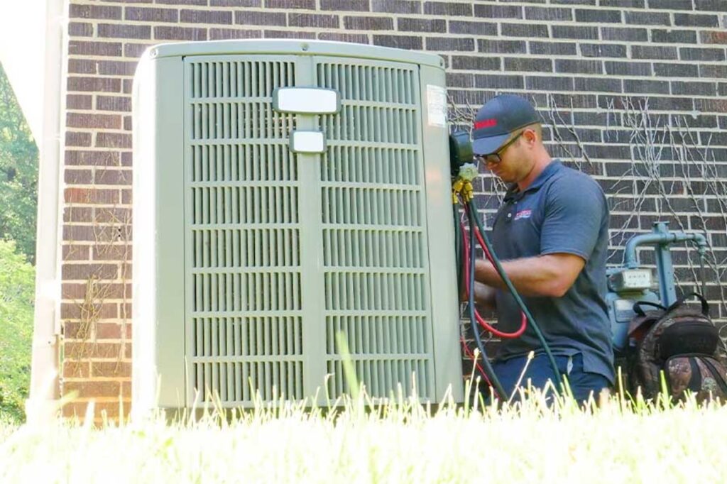hvac technician performing maintenance on ac unit outside of home